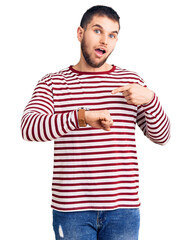 Young handsome man wearing striped sweater in hurry pointing to watch time, impatience, upset and angry for deadline delay