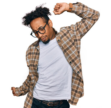 Young african american man with beard wearing casual clothes and glasses stretching back, tired and relaxed, sleepy and yawning for early morning