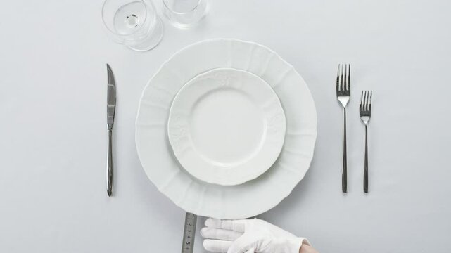Elegant table setting with white tableware plates, cutlery, and glassware for a classy dining, fancy expensive restaurant dinner