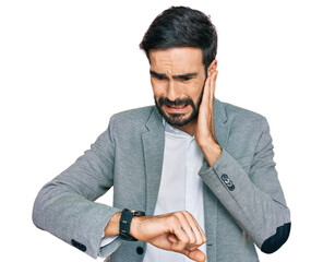 Young hispanic man wearing business clothes looking at the watch time worried, afraid of getting late