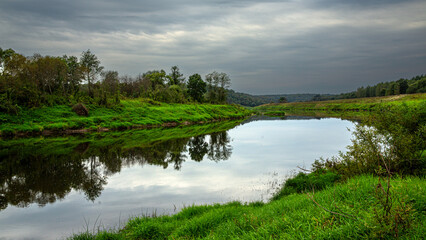 Enjoy the serene river landscape with reflective water and lush greenery in a natural environment