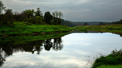 A serene river landscape with abundant green vegetation and a tranquil, reflective water surface