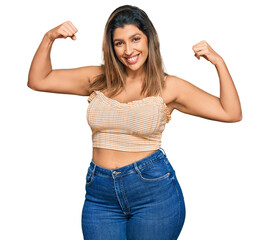 Beautiful brunette woman wearing casual clothes showing arms muscles smiling proud. fitness concept.