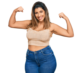 Beautiful brunette woman wearing casual clothes showing arms muscles smiling proud. fitness concept.