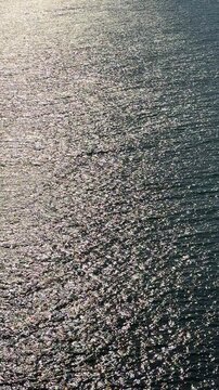 Dark glitterting water surface at night, vertical video