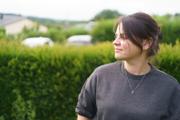 Young smiling beautiful girl with collected hair in a sweater in the backyard in summer. Happy...