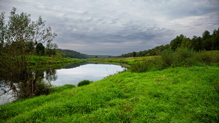 Serene riverside landscape featuring lush greenery under a cloudy sky in a tranquil setting