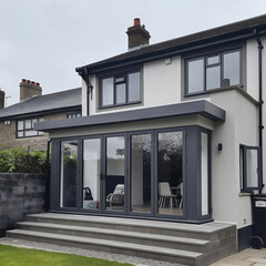 Glazed veranda with a flat roof on the external facade of an existing semi-detached house with glazing in a loft style