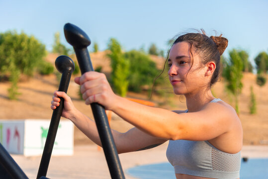 Young woman exercising on outdoor fitness equipment