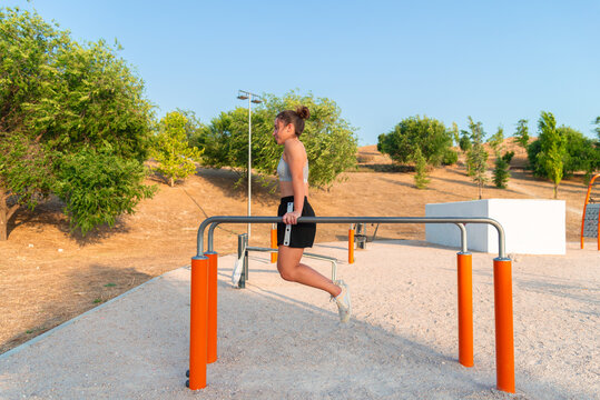 Young woman working out on parallel bars at park