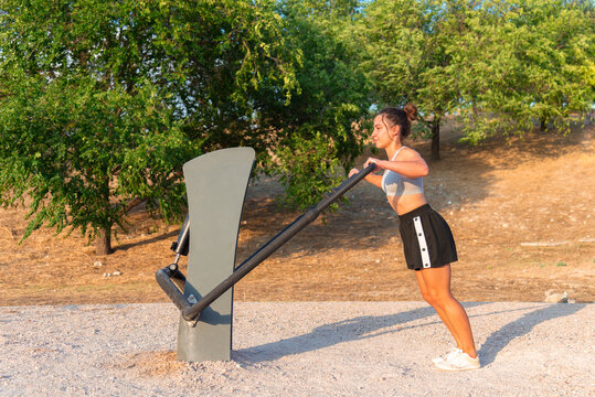 Young woman working out at outdoor gym equipment