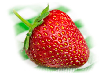 Large red strawberry on a background of a green tablecloth