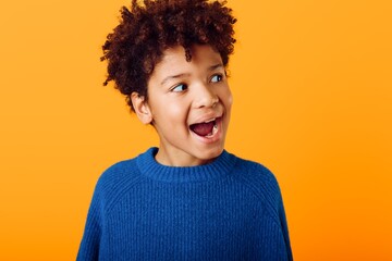 Young african american boy with wide eyes and open mouth expressing astonishment against a bright...