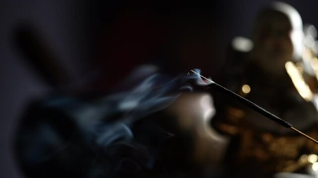 Asian incense stick in stick holder burning with smoke on dark background, close up. Meditation, yoga, self development and sound therapy concept