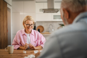 Senior couple husband and wife play dominoes together at home