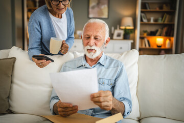 Senior man read a letter from envelope whit mature women behind him