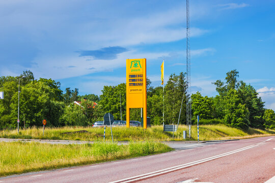 Gas station with yellow Preem sign displaying fuel prices, located by roadside with greenery and trees in background. Sweden. Europe. 