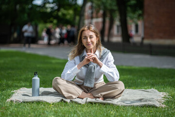 Satisfied woman resting outside in lotus position, enjoying warm sunny weather, day off, weekends...
