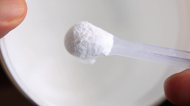 A person take a scoop from a white creatine for inspection