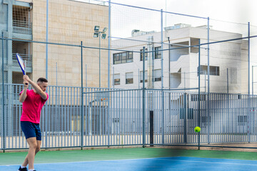 A man in a pink shirt is playing tennis on a court