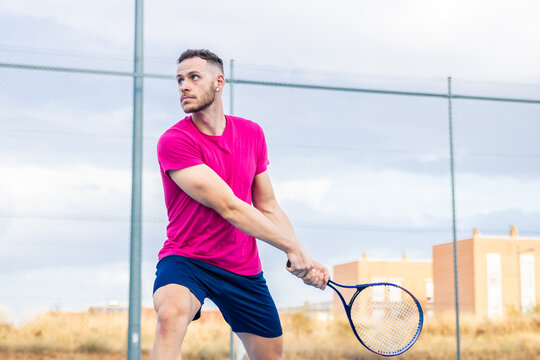 Young man executing backhand on tennis court