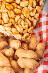 Peanuts, portion of shelled peanuts and pé-de-moleque (peanut candy) on a plate, on a green and white checkered tablecloth. Selective focus.