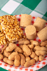 Peanuts, portions of shelled peanuts and pe-de-moleque and paçoquinha (peanut sweets) on a plate, on a green and white checkered tablecloth. Selective focus.