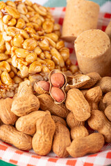 Peanuts, portions of shelled peanuts and pe-de-moleque and paçoquinha (peanut sweets) on a plate, on a green and white checkered tablecloth. Selective focus.
