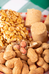 Peanuts, portions of shelled peanuts and pe-de-moleque and paçoquinha (peanut sweets) on a plate, on a green and white checkered tablecloth. Selective focus.
