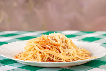 Pasta, portion of spaghetti noodles with grated cheese on a white plate on a green and white...