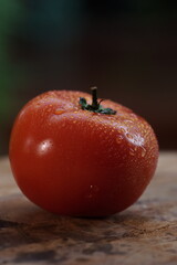 red tomato on a black background - Vertical image of a fresh tomato, close-up on dark background, with natural texture and water drops. Perfect for culinary, health, and organic-themed projects