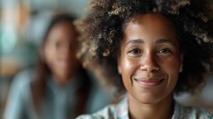 Fototapeta premium A woman with curly hair wearing a checkered shirt smiles warmly at the camera, her friendly demeanor and bright eyes reflecting a sense of joy and friendliness.