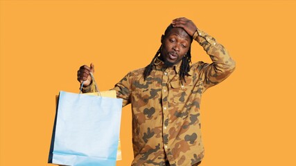 Cheerful person holding shopping paper bags in studio, buying clothes on sale at mall. Shopaholic...
