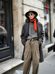 Obraz premium Stylishly dressed in street style young woman in hat and glasses poses on the city street close-up 