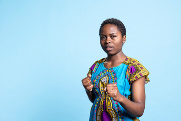 African american woman clenching fists and punching the air, showing strength and being aggressive in front of camera. Female model acting powerful and kickboxing, body training.