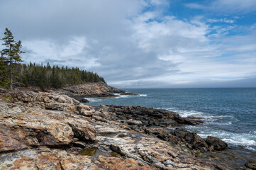 Rocky Coastline at Acadia National Park. The rocky coastline of Acadia National Park stretches out towards the Atlantic Ocean. A line of trees follows the shore, providing a contrast to the dramatic 