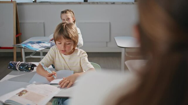 Smart pupil answering lesson learning at desk closeup. Kid writing exercise book