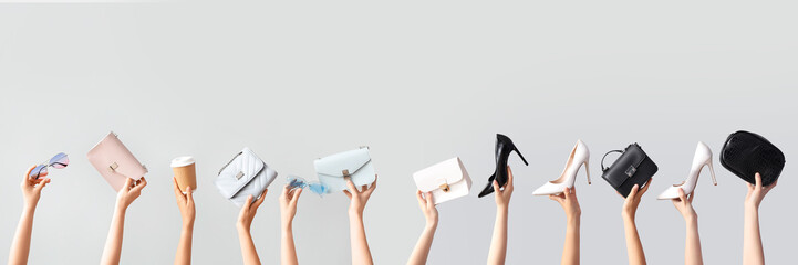 Female hands holding different stylish bags, sunglasses and cup of coffee on grey background