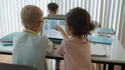 Back view of kids learning to code on laptop when attending computer group class at school