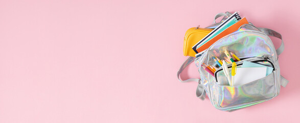 Backpack with school supplies for study isolated on pink background. Back to school concept. Full school backpack. Flat lay, top view
