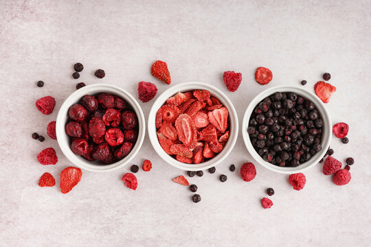 Composition with bowls of tasty freeze-dried berries on light background