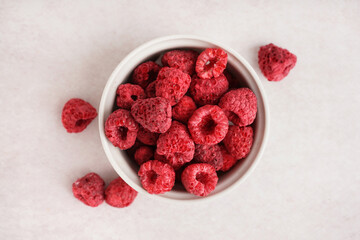 Bowl with tasty freeze-dried raspberries on light background