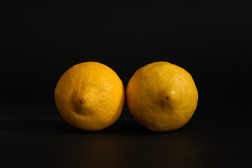Fresh ripe lemons on dark background. Erotic and female health care concept