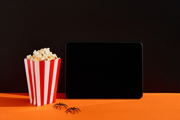 Striped box with popcorn and tablet on an orange black background