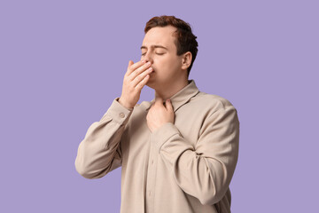 Young man with sore throat on lilac background