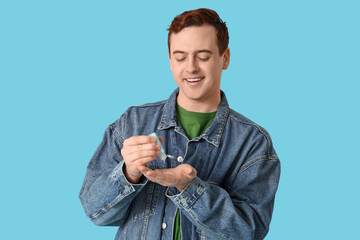 Young man with sanitizer on blue background