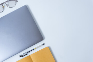 Flat lay photo of office desk with laptop, eyeglasses, pen, and notebook with copy space background. Mockup