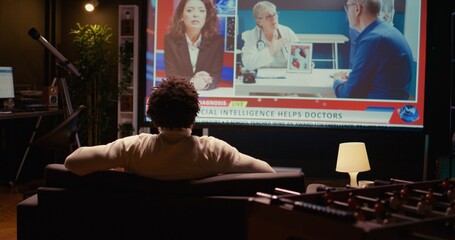 African american man watching news program on modern TV about artificial intelligence subject, zoom...