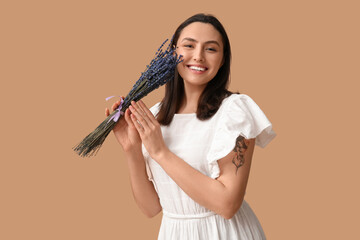 Beautiful happy young woman with bouquet of lavender flowers on beige background