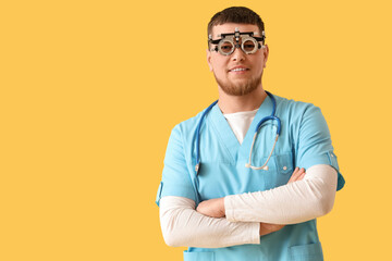 Male ophthalmologist with trial frame on yellow background